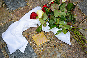 Das Foto zeigt einen mit Rosen geschmückten Stolperstein vor dem Gebäude Rindermarkt 20, gewidmet Wilhelmine Krippner.
